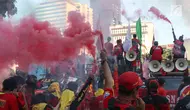 Sejumlah buruh menyalakan bom asap saat menutup aksi Hari Buruh Internasional di Jalan Medan Merdeka Barat, Jakarta, Rabu (5/1/2019). Aksi May Day 2019 di Jakarta ditutup oleh buruh dengan menyalakan kembang api sebagai simbol berjalannya demo dengan damai. (Liputan6.com/Helmi Fithriansyah)