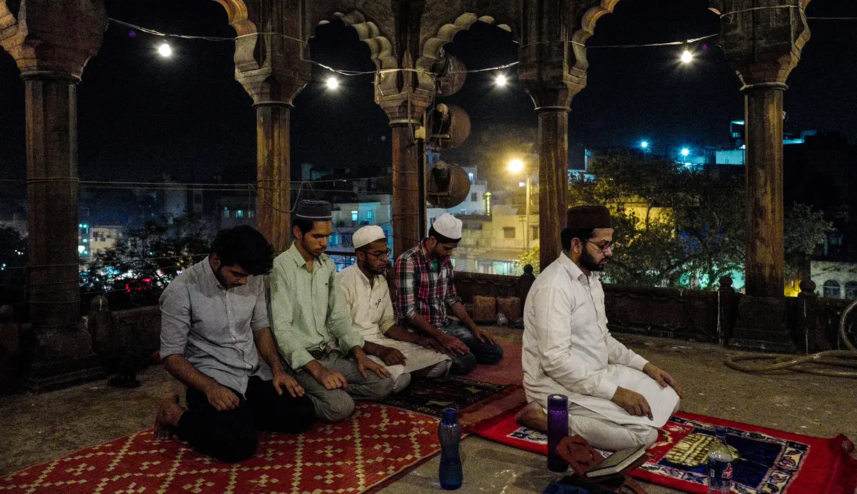 Jemaah pria muslim India menjalankan salat tarawih selama bulan suci Ramadan di Masjid Jama di New Delhi, India (23/5). Seperti jutaan muslim di seluruh dunia, muslim India juga menjalankan salat Terawih pada malam bulan Ramadan. (AFP/Chandan Khanna)