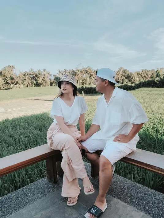 Untuk OOTD liburan, kamu bisa tiru gaya Chelsea dan Glenn yang satu ini. Chelsea tampak memadukan blouse putih dengan high waist pants warna krem, serta bucket hat warna senada. Sementara Glenn tampil serba putih memadukan kemeja, short pants, dan topi. (Instagram/chelseaoliviaa).