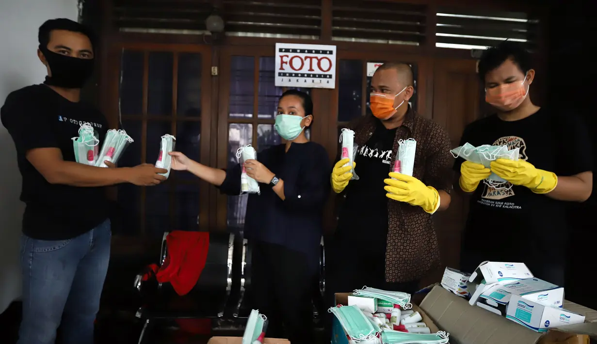 Ketua Pewarta Foto Indonesia (PFI) Reno Esnir (kedua kanan) membagikan masker dan hand sanitizer kepada jurnalis foto di Jakarta, Jumat (20/3/2020). PFI membagikan 1.000 masker dan 500 botol hand sanitizer kepada lebih dari 190 jurnalis foto di DKI Jakarta. (Foto: Dok. Pewarta Foto Indonesia)