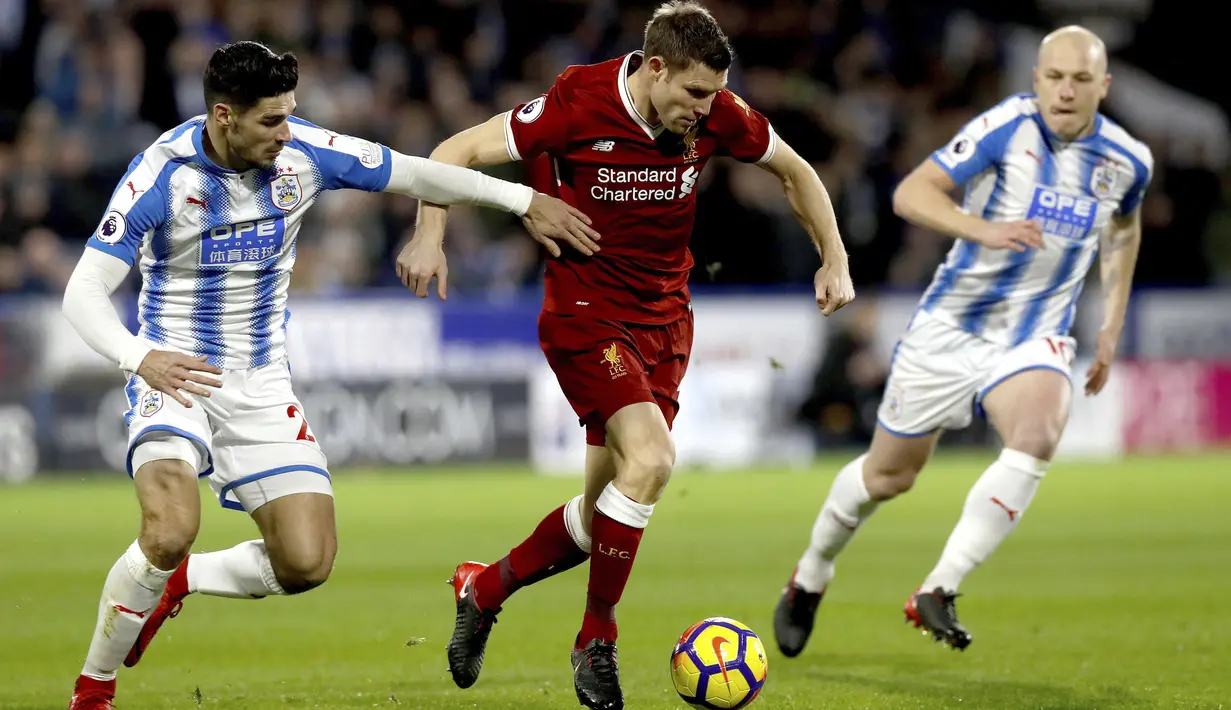 Pemain Liverpool, James Milner (tengah) mencoba melewati adangan dua pemain Huddersfield Town pada lanjutan Premier League di John Smith's Stadium, Huddersfield, (30/1/2018). Liverpool menang 3-0. (Martin Rickett/PA via AP)