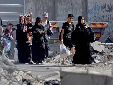 Warga Palestina dengan barang-barang mereka mengungsi ke daerah yang lebih aman di kota Gaza setelah serangan udara Israel, pada 13 Oktober 2023. (MOHAMMED ABED/AFP)