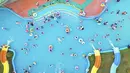 Suasana foto udara warga China bersantai di kolam renang Lianyungang, provinsi Jiangsu timur, China (4/7/2021). Di tengah pandemi Covid-19, warga China asyik menonton pertunjukan papan luncur saat mereka mendinginkan diri di kolam renang sambil bersantai. (AFP/STR)