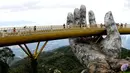 Pengunjung berjalan di sepanjang Golden Bridge di Perbukitan Ba Na dekat Danang, Vietnam, Selasa (31/7). Golden Bridge juga disebut-sebut sebagai Jembatan Tangan Tuhan karena ada dua tangan raksasa yang menopangnya. (Linh PHAM/AFP)