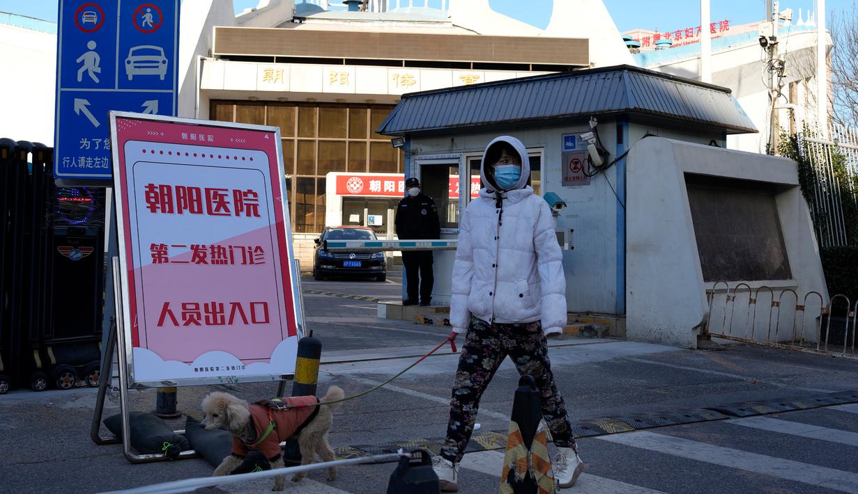 Seorang warga berjalan-jalan dengan anjingnya melewati klinik demam kedua yang baru dibuka di Rumah Sakit Chaoyang, Beijing, China, Kamis (15/12/2022). Seminggu setelah China melonggarkan beberapa tindakan pengendalian COVID-19 yang paling ketat di dunia, ketidakpastian masih ada mengenai arah pandemi di negara dengan jumlah penduduk terpadat di dunia tersebut. (AP Photo/Ng Han Guan)