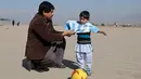 Murtaza Ahmadi (5), bocah asal Afghanistan, dibantu ayahnya memakai jersey yang ditandatangani langsung oleh bintang Barcelona, Lionel Messi, ketika bersiap main sepak bola di sebuah lapangan terbuka di Kabul, Jumat (26/2). (REUTERS/Omar Sobhani)