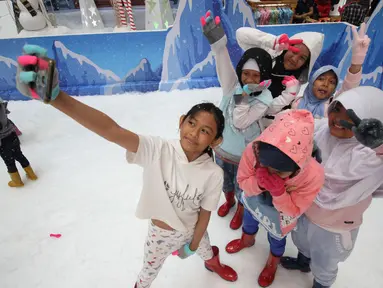 Anak-anak berselfie saat bermain sajlu di Snow Village di salah satu pusat perbelanjaan di kawasan Tangsel, Senin (17/12). Jelang Natal dan Tahun Baru sejumlah pusat perbelanjaan menyajikan kegiatan untuk menarik pengunjung. (Merdeka.com/Arie Basuki)