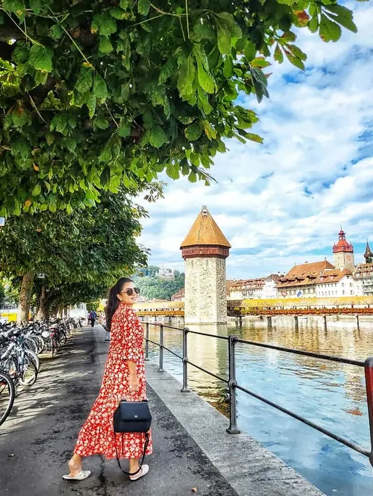 Mayangsari menyusuri jalan di Lucerne, Swiss, di mana banyak sepeda diparkir dan dari seberang kali terlihat gedung tua. (Foto: Instagram/@mayangsari_official)