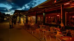 Orang-orang minum di pasar Naschmark yang biasanya penuh sesak di Wina, Austria pada 5 Oktober 2020. Naschmarkt adalah pasar tertua, terbesar, dan terpopuler di Wina kini sepi pengunjung akibat pandemi corona COVID-19. (JOE KLAMAR / AFP)