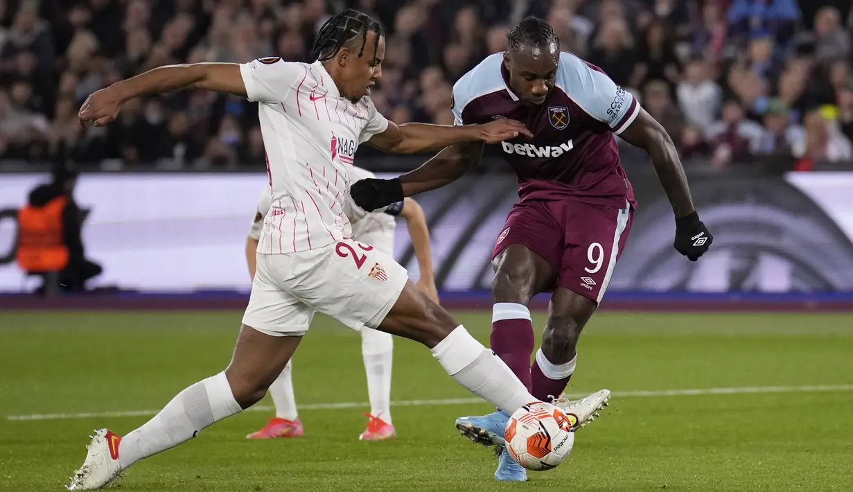 Penyerang West Ham Michail Antonio melakukan tendangan  ke gawang di bawah tekanan bek Sevilla Jules Kounde pada leg kedua Liga Europa 2021/2022 di Stadion London, Jumat (18/3/2022) dini hari WIB. West Ham United menang dramatis atas Sevilla dengan skor 2-0. (AP Photo/Matt Dunham)