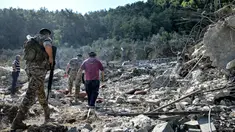 Tentara tentara Lebanon dan lainnya berjalan melewati reruntuhan bangunan yang hancur di lokasi serangan udara Israel sebelumnya di desa Aito, Lebanon utara pada 15 Oktober 2024. (JOSEPH EID/AFP)