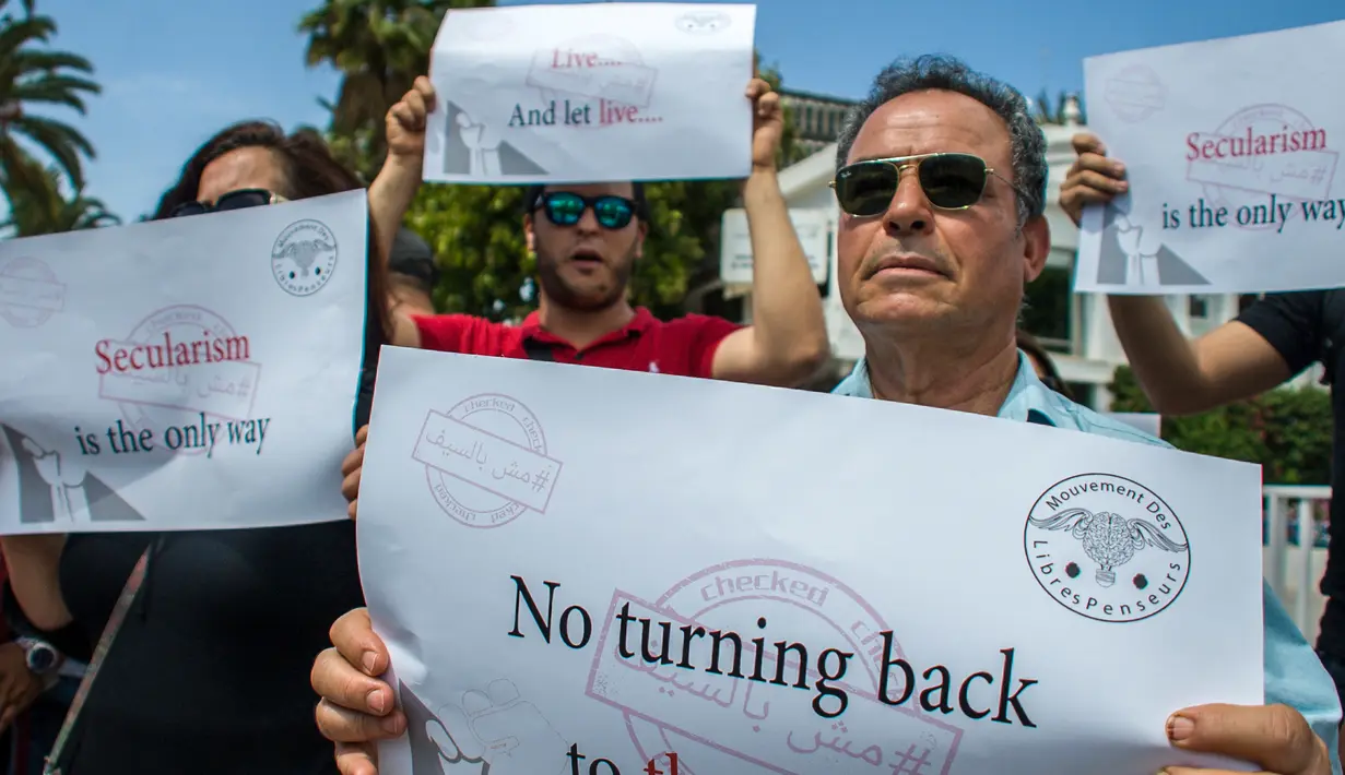 Seorang demonstran Tunisia saat melakukan aksi unjuk rasa  protes terhadap pemilik restoran dan bar yang menutup tokonya selama puasa bulan suci Ramadan di Tunis, Tunisia, (27/5). (AP Photo / Hassene Dridi)