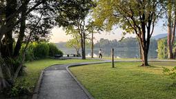 Seorang warga berolahraga di bawah rindangnnya pepohonan di tepi Danau Angkaew di Chiang Mai, Thailand, Senin (8/12/2025). (Bola.com/Bagaskara Lazuardi)