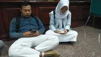 Anin dan Afif beristirahat setelah dipingpong saat hendak mendaftar ujian nasional di SMA Negeri 1 Semarang. (foto : Liputan6.com / edhie prayitno ige)