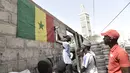 Pendukung menggantung bendera nasional Senegal di luar bengkel ban di Dakar (4/2/2022). Senegal akan bertanding melawan Mesir pada babak final Piala Afrika 2021 di Paul Biya stadium, Senin (7/2/2022) dini hari WIB besok. (AFP/Seyllou)