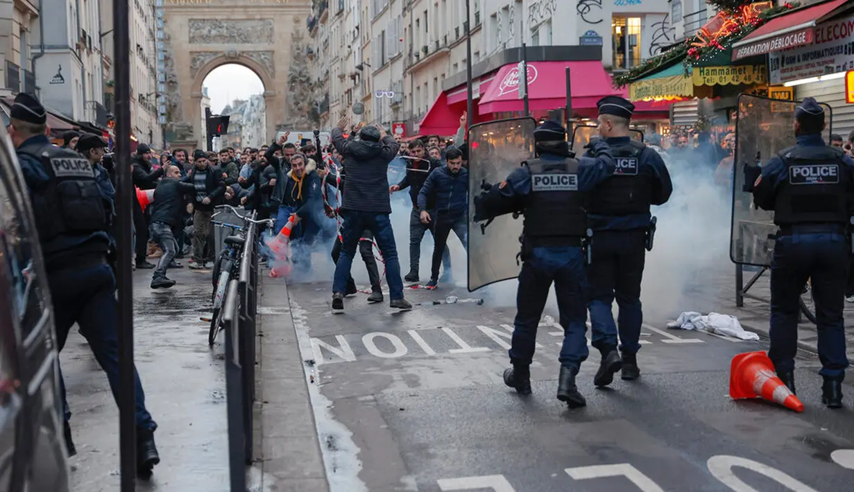 Anggota komunitas Kurdi bentrok dengan petugas polisi di TKP tempat terjadinya penembakan di Paris, Prancis, 23 Desember 2022. Polisi menuturkan 11 petugas terluka akibat bentrokan itu. (AP Photo/Lewis Joly)