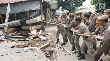 Petugas Satpol PP menarik tali untuk merobohkan bangunan liar di Jalan Desa Semanan, Kalideres, Jakarta Barat, Senin (9/4). Penertiban dilakukan karena bangunan liar tersebut berdiri di atas tanah saluran air. (Liputan6.com/Arya Manggala)