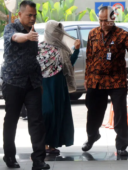 Kasi Dinkes Bengkulu Selatan Wati mendapat pengawalan petugas saat tiba di Gedung KPK, Jakarta, Rabu (16/5). Wati merupakan keponakan Bupati Bengkulu Selatan Dirwan Mahmud. (Merdeka.com/Dwi Narwoko)