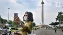 Warga berswafoto saat berkunjung pada hari perdana uji coba pembukaan Monumen Nasional (Monas), Jakarta Pusat, Kamis (16/6/2022). Pasca ditutup sejak 2020 akibat pandemi Covid-19, Pemprov DKI Jakarta melakukan uji coba pembukaan kawasan wisata Monas secara bertahap dan terbatas yang dimulai dari kawasan luar tugu. (merdeka.com/Iqbal S Nugroho)