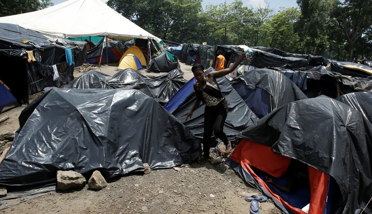 Seorang wanita migran asal Afrika yang terdampar di Kosta Rika berjalan di antara tenda-tenda di kamp darurat di perbatasan antara Kosta Rika dan Nikaragua, di Penas Blancas, Kosta Rika, (14/7). (REUTERS / Juan Carlos Ulate)