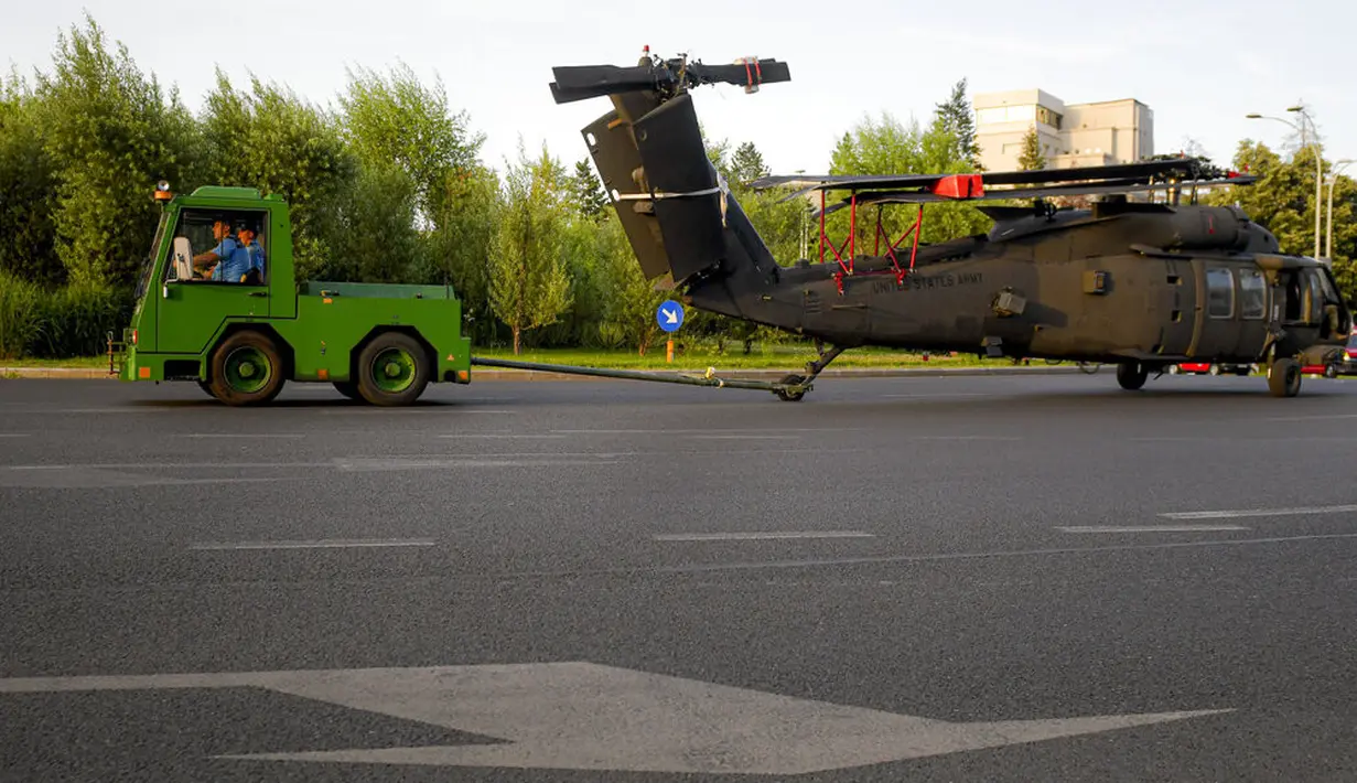 Prajurit menderek helicopter Black Hawk militer AS yang mendarat darurat di boulevard yang sibuk, di Bucharest, Rumania, Kamis (15/7/2201). Pendaratan tersebut merusak dua mobil setelah merobohkan dua tiang lampu namun tidak ada korban yang dilaporkan. (AP Photo/Andreea Alexandru)