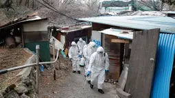 Tentara Korea Selatan yang mengenakan pakaian pelindung menyemprotkan desinfektan di gang-gang permukiman di Seoul, Selasa (3/3/2020). Seoul mengerahkan tentara untuk menyemprotkan disinfektan di jalan dan gang-gang untuk mencegah penyebaran virus corona COVID-19. (AP Photo/Lee Jin-man)