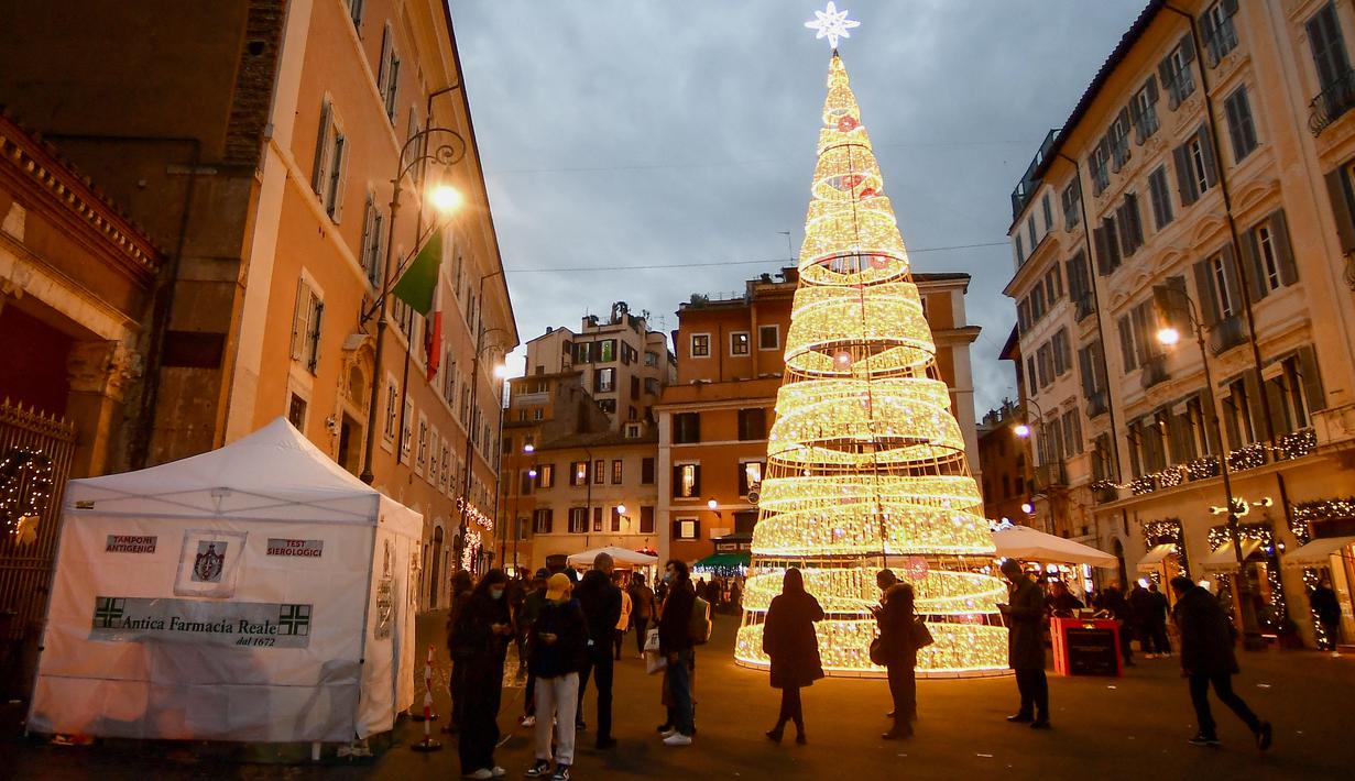 Orang-orang menunggu di luar apotek untuk dites Covid-19 sebelum Natal, di Roma, Italia pada Kamis (23/12/2021). Pemerintah Italia telah mewajibkan kembali penggunaan masker di luar ruangan untuk menahan peningkatan kasus Covid-19 yang didorong oleh varian Omicron. (Filippo MONTEFORTE/AFP)