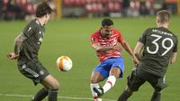 Gelandang Granada, Yangel Herrera (tengah) melepaskan tendangan ke gawang Manchester United dalam laga leg pertama perempatfinal Liga Europa 2020/2021 di Nuevo Los Carmenes Stadium, Granada, Kamis (8/4/2021). Granada kalah 0-2 dari Manchester United. (AFP/Cristina Quicler)