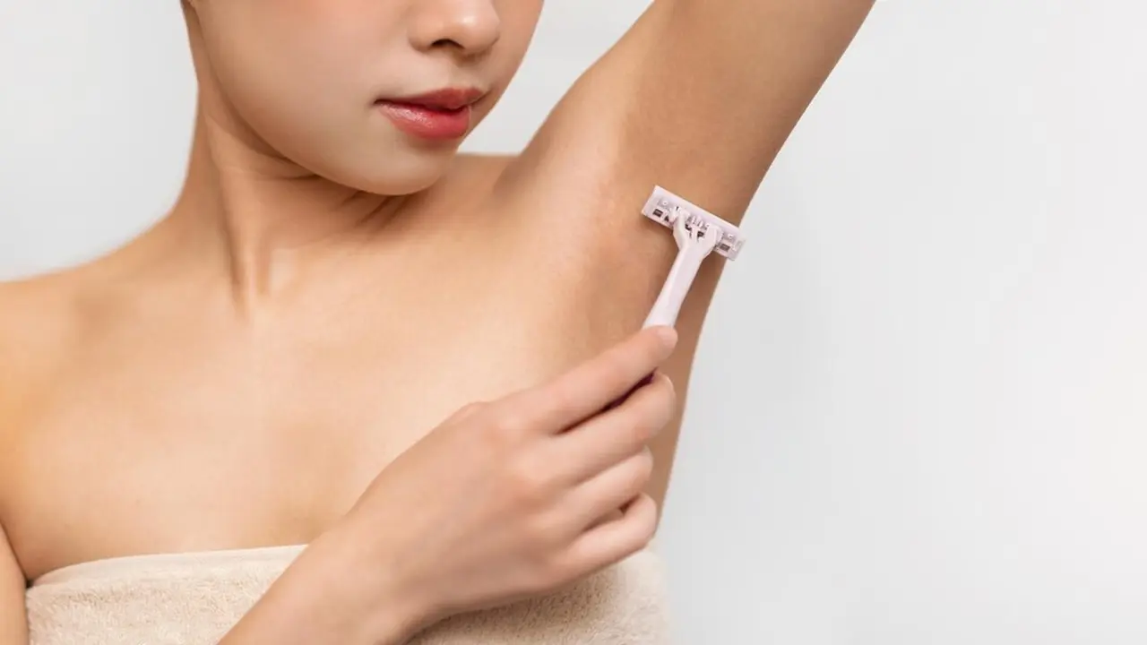 Seorang wanita tampak sedang mencukur bulu ketiaknya (Foto Dok: Freepik/prostock-studio)