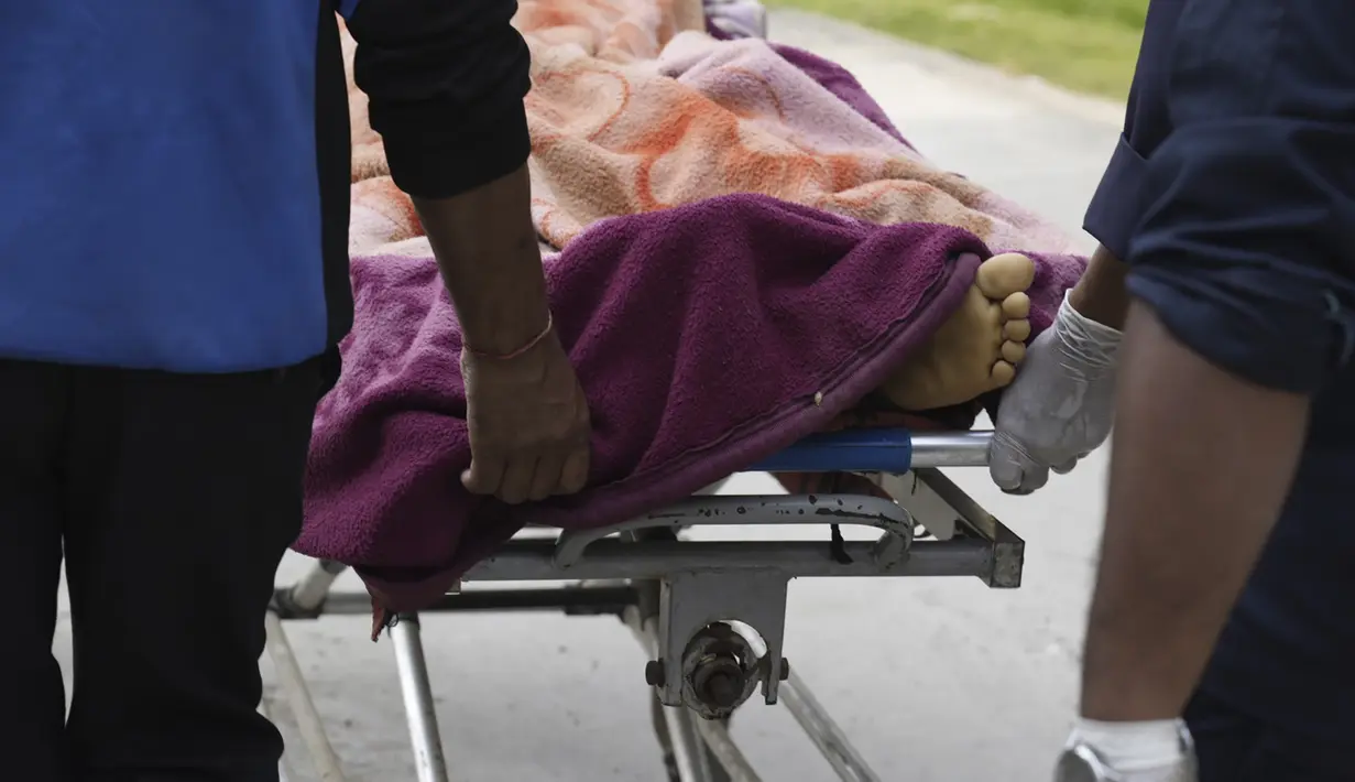 Petugas keamanan bekerja sama dengan penduduk desa sepanjang malam dalam kegelapan untuk menarik korban tewas dan terluka dari rumah-rumah yang roboh. (AP Photo/Niranjan Shrestha)