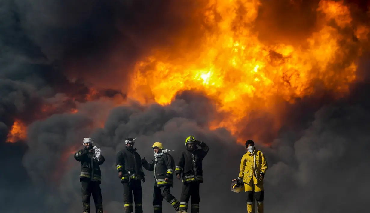 Petugas pemadam kebakaran saat berusaha memadamkan api di salah satu tangki minyak yang terbakar di pelabuhan Es Sider, Libya, (6.1).  Diduga penyebab kebakaran adalah serangan yang dilakukan oleh kelompok militan. (REUTERS / Stringer)