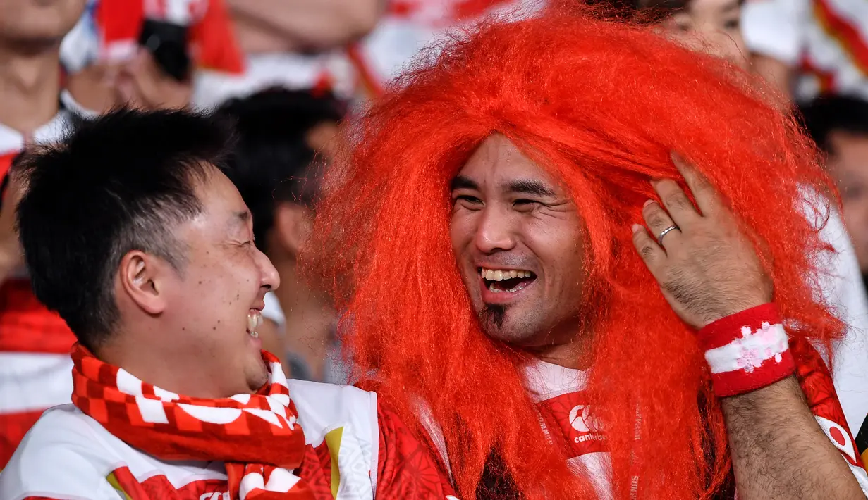 Seorang fans mengenakan rambut palsu tertawa dengan rekannya sebelum pertandingan antara Rusia dan Jepang pada pembukaan Rugby World Cup Pool A  di Stadion Tokyo (20/9/201). Rugby World Cup diselenggarakan dari 20 September hingga 2 November 2019. (AFP Photo/Toshifumi Kitamura)