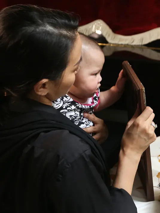Meski anak yang baru berusia tiga bulan itu belum mengerti kalau papanya meninggal dunia, Abigail Cattaleya sering rewel tidak biasanya sepeninggal papanya. Lantas Ririn mencoba mendekatkan pada foto papanya. (Bambang E. Ros/Bintang.com)