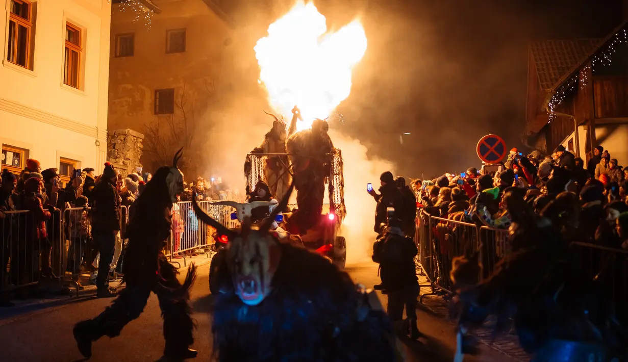 Orang-orang menyaksikan parade "The Hike of the Krampus of Three Lands" di Podkoren, Slovenia, Jumat (30/11). Parade bagian dari tradisi natal itu menghadirkan sosok Krampus, makhluk setengah iblis, untuk menakuti anak-anak yang nakal. (Jure Makovec/AFP)