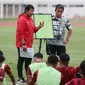 Pelatih kepala Timnas Indonesia U-19, Indra Sjafri (kiri) didampingi asisten pelatih, Bima Sakti memberi pengarahan kepada para pemainnya dalam rangkaian pemusatan latihan Timnas Indonesia U-19 di Stadion Madya, Senayan, Jakarta, Senin (1/7/2024) sebagai persiapan menghadapi ajang Piala AFF U-19 2024 yang akan berlangsung pada 17 hingga 29 Juli 2024. (Bola.com/M Iqbal Ichsan)