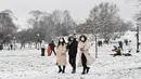 Orang-orang yang mengenakan masker berjalan di atas salju di Primrose Hill di London saat ibu kota mengalami hujan salju yang jarang terjadi pada Minggu (24/1/2021). Hujan salju langka itu membawa kegembiraan di tengah penguncian atau penutupan wilayah (lockdown) secara nasional. (JUSTIN TALLIS/AFP)