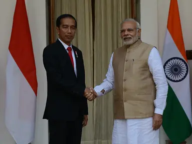 Presiden Joko Widodo (Jokowi) berjabat tangan dengan PM India Narendra Modi sebelum melakukan pertemuan bilateral di Hyderabad House, New Delhi, Senin (12/12). Ini pertama kalinya Presiden Jokowi melakukan kunjungan kenegaraan ke India. (Money SHARMA/AFP)
