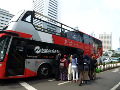 Warga antre untuk menaiki bus tingkat Transjakarta dengan atap terbuka di Jakarta, Selasa (10/5/2022). Selama libur Lebaran, bus wisata tersebut melayani warga menuju berbagai rute destinasi wisata Ibu Kota. (merdeka.com/Imam Buhori)