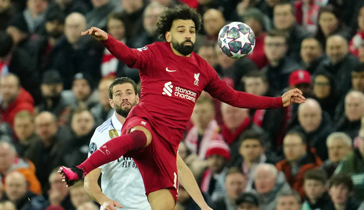 Pemain Liverpool Mohamed Salah (kanan) mengontrol bola melewati pemain Real Madrid Nacho pada pertandingan sepak bola leg pertama babak 16 besar Liga Champions di Stadion Anfield, Liverpool, Inggris, 21 Februari 2023. Real Madrid mengalahkan Liverpool dengan skor 5-2. (AP Photo/Jon Super)