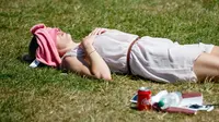 Seorang wanita Inggris berjemur di atas rumput sambil menikmati sinar matahari di Green Park, London, Senin (25/6). Pada Juli 2018, suhu di ibu kota London tercatat 29.1 derajat Celcius dan diprediksi akan mencapai 30 derajat Celcius. (AFP/Tolga Akmen)