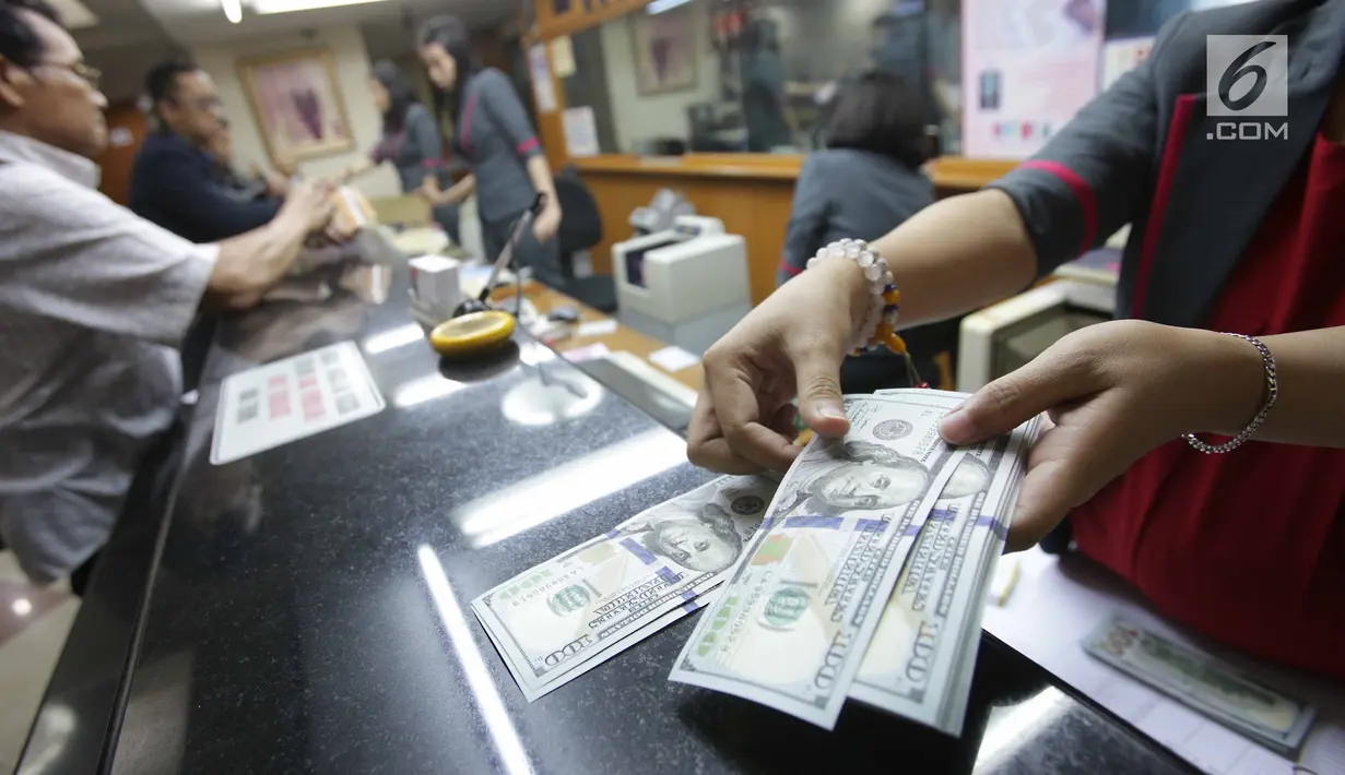 Teller menghitung mata uang dolar di Jakarta, Jumat (2/2). Deputi Gubernur BI Senior Mirza Adityaswara mengatakan, bahkan sebelum fluktuasi yang terjadi beberapa hari ini, rupiah sudah undervalue. (Liputan6.com/Angga Yuniar)