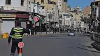 Seorang polisi memegang tanda berhenti di jalan yang hampir sepi di ibu kota Yordania, Amman, selama penguncian virus corona. [Khalil Mazraawi / AFP]