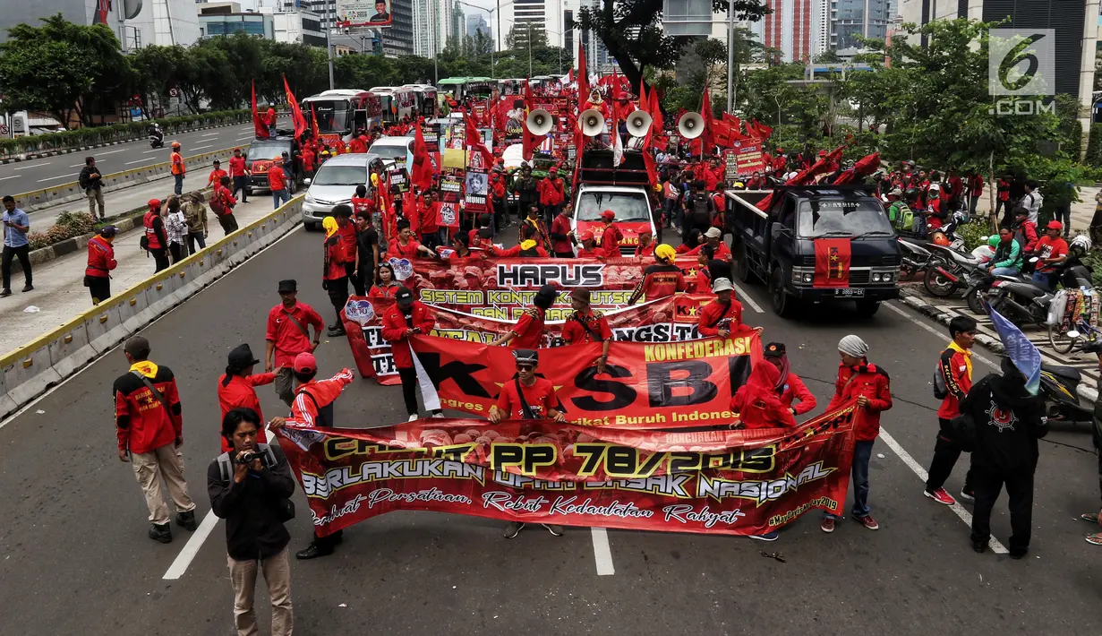 Peserta aksi dari sejumlah elemen buruh membentangkan poster dan spanduk aksi memperingati Hari Buruh Sedunia di kawasan Bundaran HI, Jakarta, Rabu (1/5/2019). Massa aksi dalam peringatan Hari Buruh 2019 tidak dapat mendekati Istana Merdeka lantaran tertahan di kawasan itu. (Liputan6.com/Johan Tallo