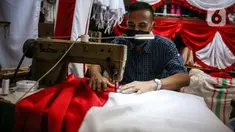 Pekerja menjahit bendera merah putih di kiosnya, kawasan Pasar Senen, Jakarta, Rabu (5/8/2020). Menjelang peringatan HUT ke-75 Kemerdekaan RI, sejumlah pedagang mengaku penjualan pernak-pernik bendera merah putih menurun 50 persen dibanding tahun lalu akibat COVID-19. (Liputan6.com/Faizal Fanani)