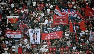 Suporter mengibarkan bendera dan membentangkan spanduk di tribun penonton selama pertandingan Premier League antara Manchester United dan Arsenal di Old Trafford, Manchester, Inggris barat laut, pada 17 Agustus 2025. (Paul ELLIS/AFP)