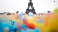 Sejumlah orang melempar bubuk berwarna saat merayakan akhir perlombaan Color Run 2018 di depan Menara Eiffel di Paris, Prancis (15/4). Dengan acara ini sekitar Menara Eiffel terlihat berwarna-warni. (AP/Thibault Camus)