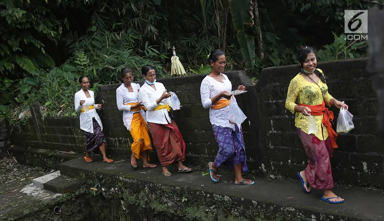 Sejumlah wanita saat akan beribadah di sekitar Sungai Yeh Sah, Desa Batusesa, Kec Rendang, Karangasem, Bali, Jumat (1/12). Warga berharap diberi keselamatan dan berkah dari erupsi Gunung Agung yang terjadi. (Liputan6.com/Immanuel Antonius)