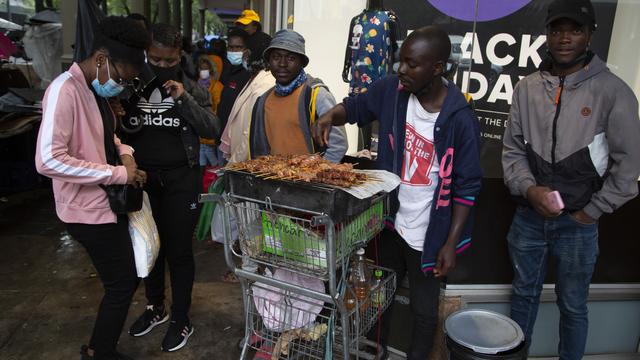 Seorang wanita membeli ayam di trotoar yang ramai di Pretoria, Sabtu (27/11/2021). Saat dunia bergulat dengan munculnya varian baru COVID-19, para ilmuwan di Afrika Selatan —tempat Omicron pertama kali diidentifikasi — berjuang keras memerangi penyebarannya ke seluruh negeri (AP Photo/Denis Farr