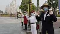 Pegawai mengenakan masker saat menyambut wisatawan di taman hiburan Disneyland, Shanghai, China, Senin (11/5/2020). Disneyland Shanghai kembali dibuka setelah tiga bulan ditutup akibat pandemi virus corona COVID-19. (AP Photo/Chen Si)