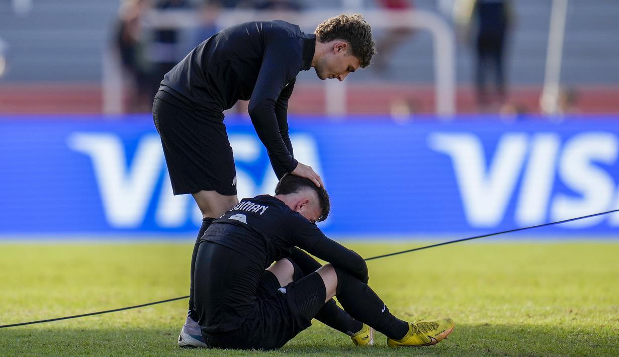 Gelandang Timnas Selandia Baru U-20, Jay Herdman (bawah) dihibur rekannya setelah dikalahkan Amerika Serikat pada laga babak 16 besar Piala Dunia U-20 2023 di Malvinas Argentinas Stadium, Mendoza, Argentina, Rabu (31/5/2023) dini hari WIB. (AP Photo/Natacha Pisarenko)